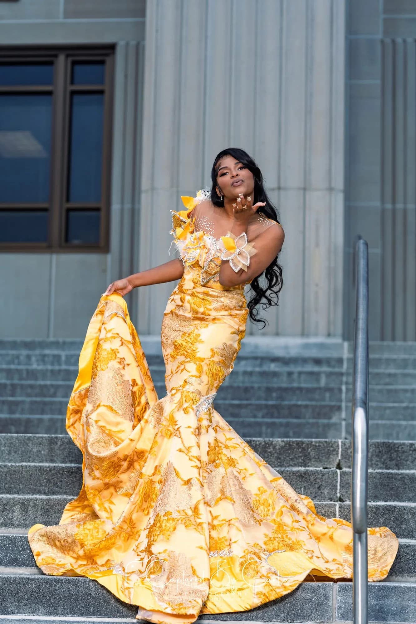 Client wearing a gold floral gown with a sculptural train