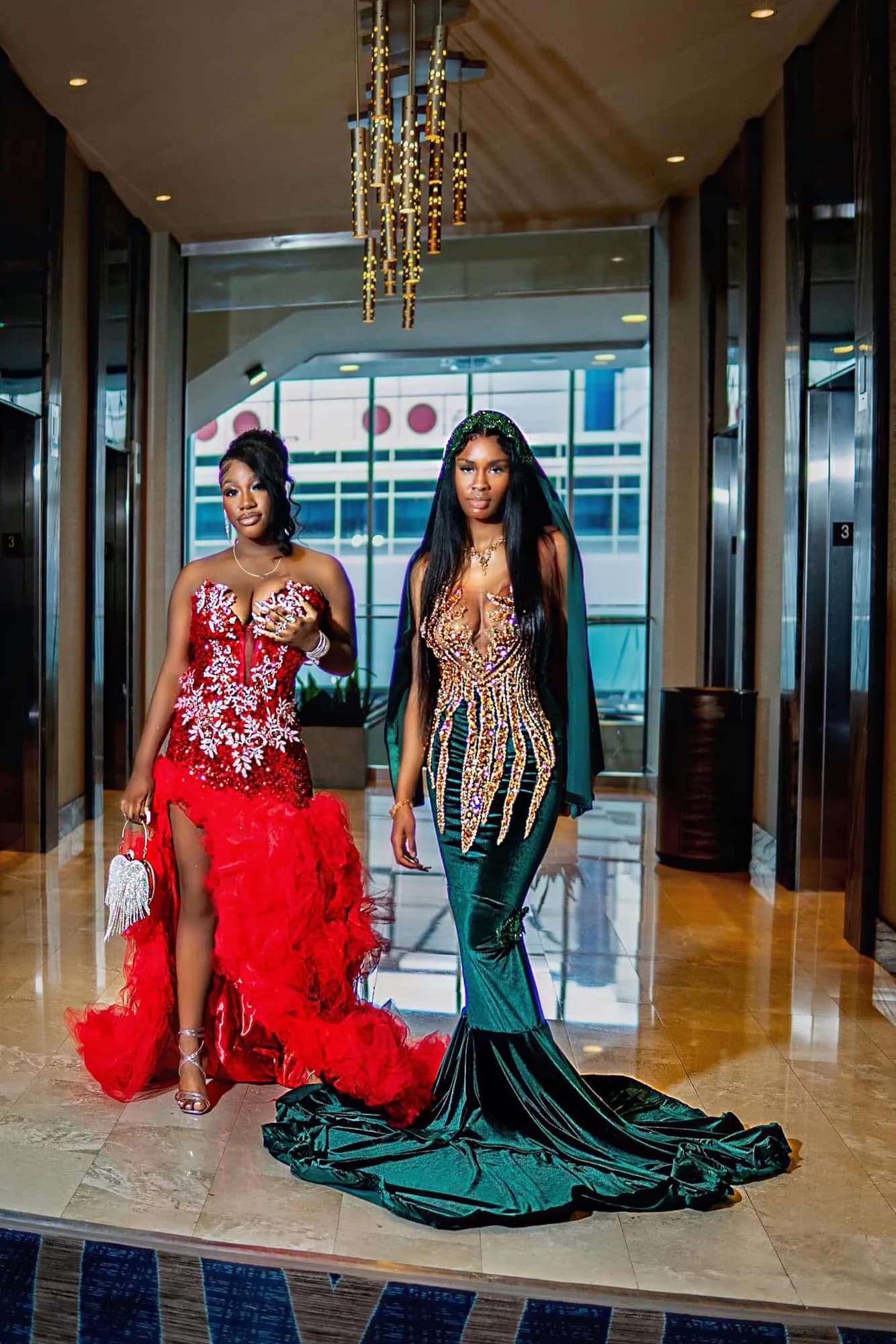 Two clients wearing red and emerald embellished gowns