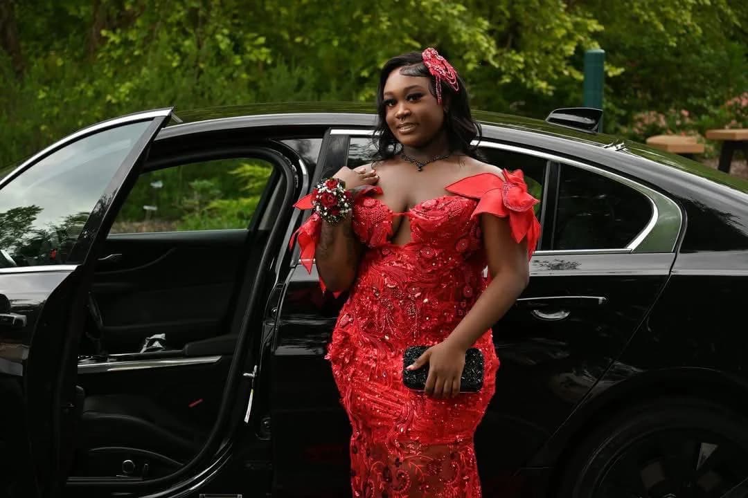 Client wearing a red embellished gown beside a black car